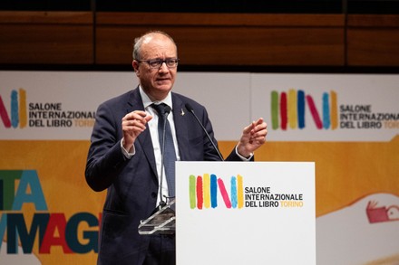 Giuseppe Valditara speaking at a lectern on stage at the inauguration of the 36th Salone Internazionale del Libro in Turin