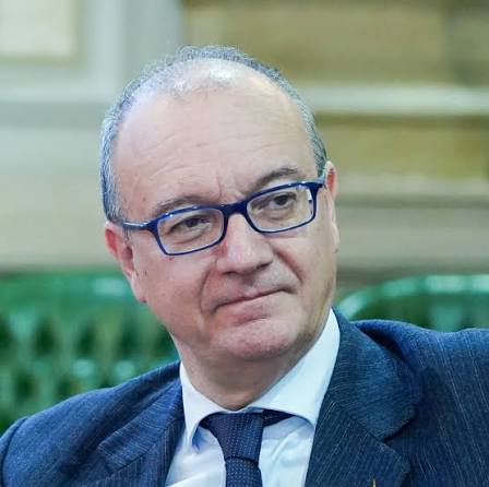 Close portrait of Giuseppe Valditara wearing glasses and a dark suit, with a thoughtful expression